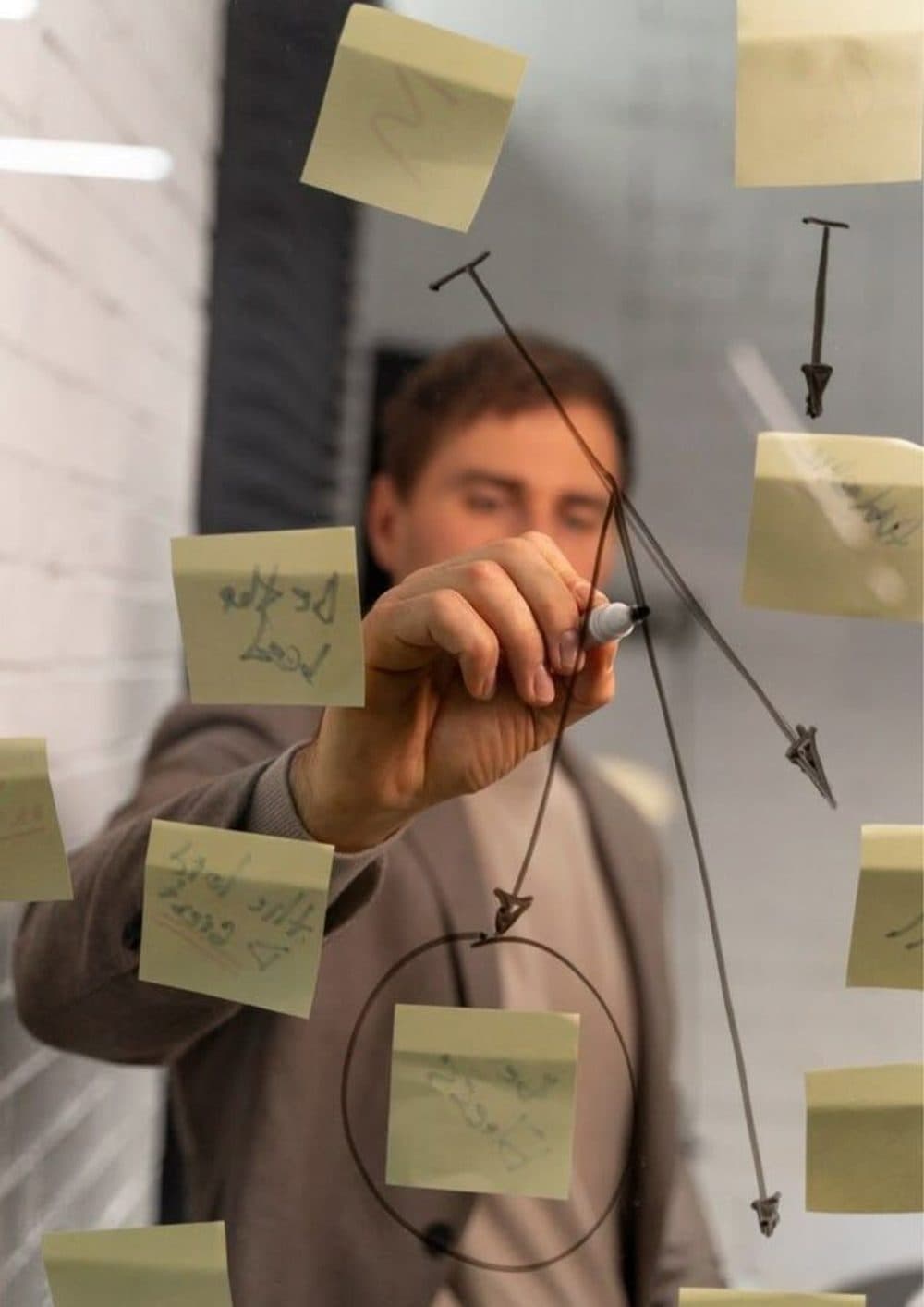 Mapping a project roadmap on a glass wall covered in sticky notes